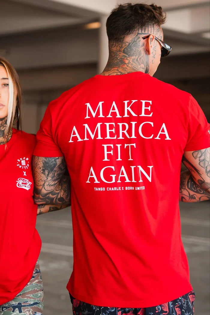 Wearing a bold red Make America Fit Again - Tee from Tango Charlie Apparel, a man stands in a parking garage. His tattoos and sunglasses complete his standout look as he promotes health, wellness, and preventive care.