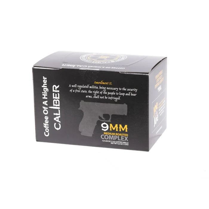 Caliber Coffee Companys black coffee box features Coffee of A Higher Caliber with a gun silhouette. It highlights the 9MM Medium Roasted Complex, nodding to the Second Amendment, and offers medium roast Colombian coffee in single-serve portions.