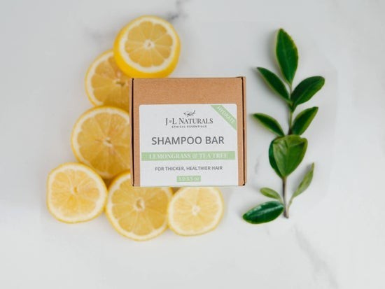 Tea-Shirt Shoppe natural shampoo bar in eco-friendly packaging with fresh lemon slices and green leaves.